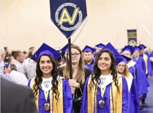 Graduates in line with the AV seal on a flag above